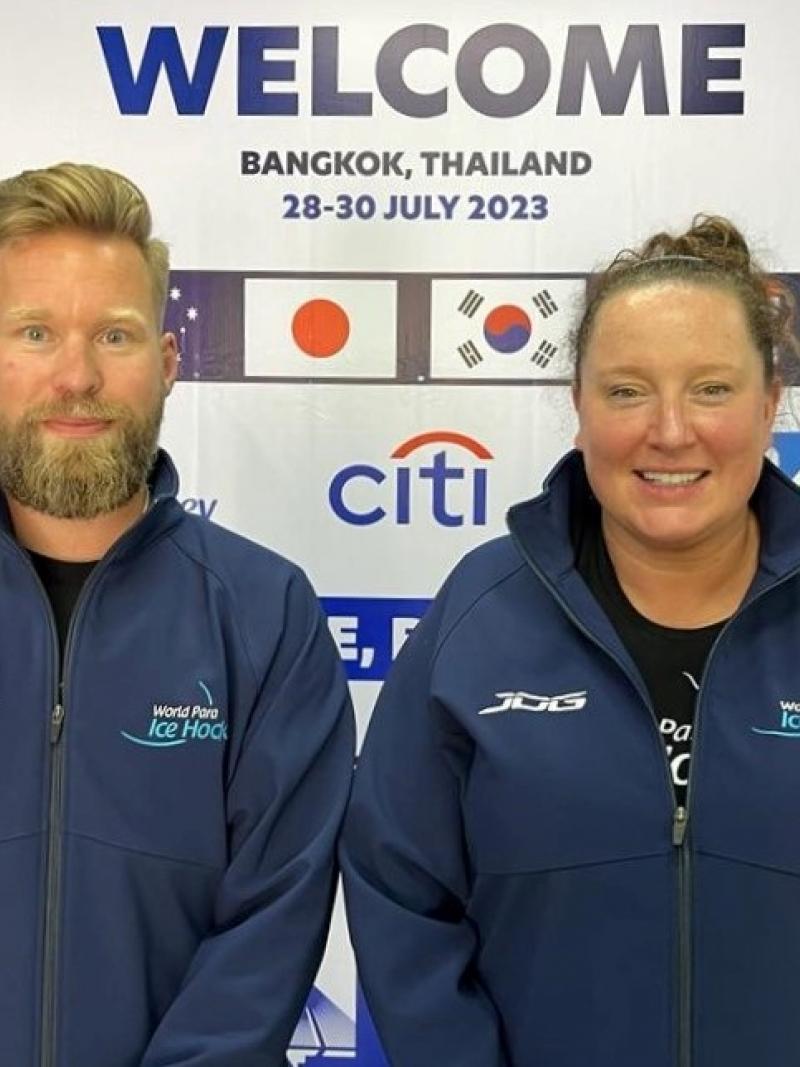 A man and a woman standing in front of a Welcome backdrop 
