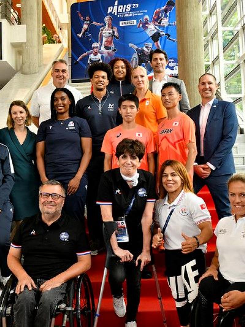 Fifteen athletes and officials pose for a photograph 