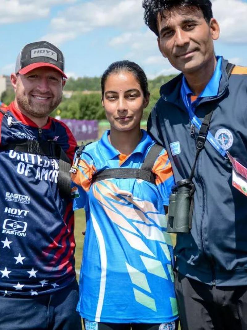 Three people, including a male and female archers, pose in front of a camera.