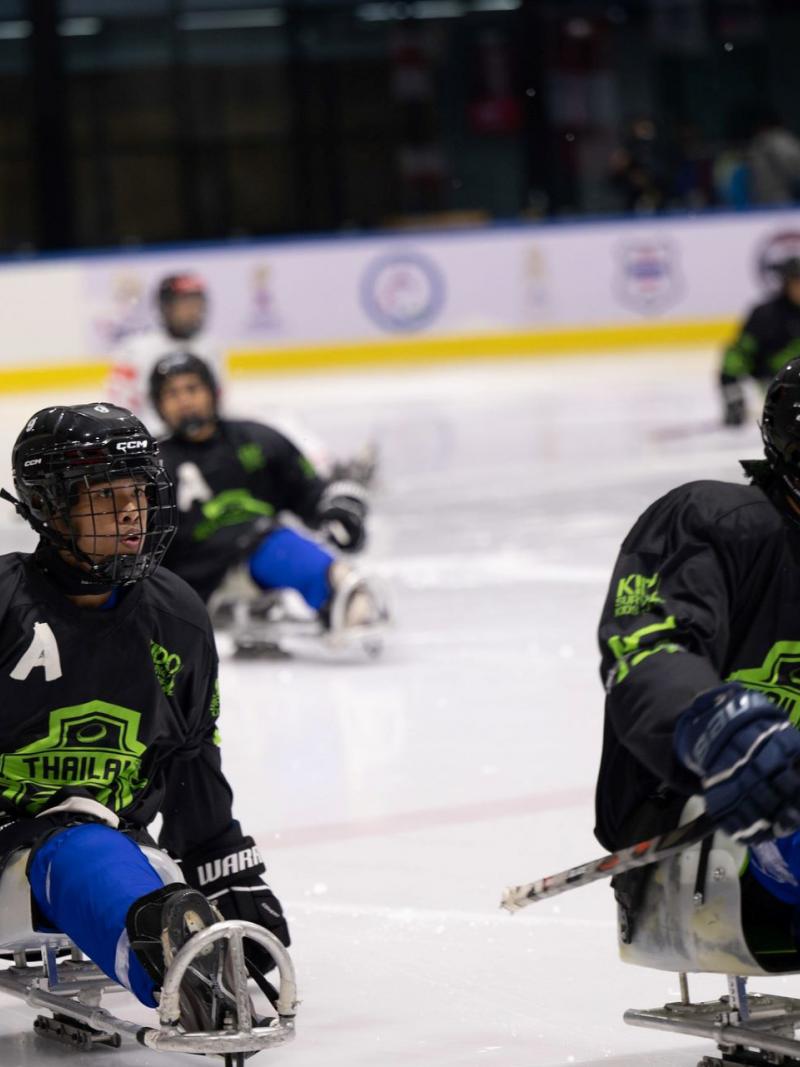 Three Thai Para ice hockey players in a game on ice
