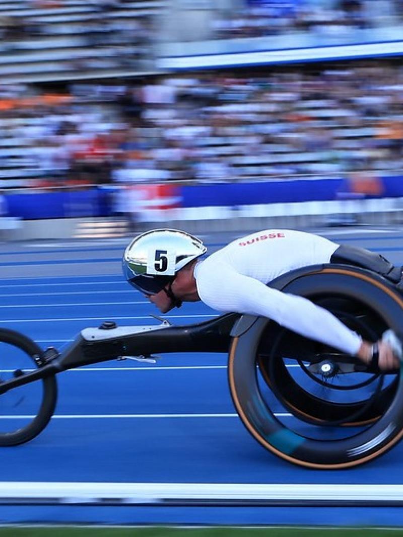 A male wheelchair racer running in front of the crowd