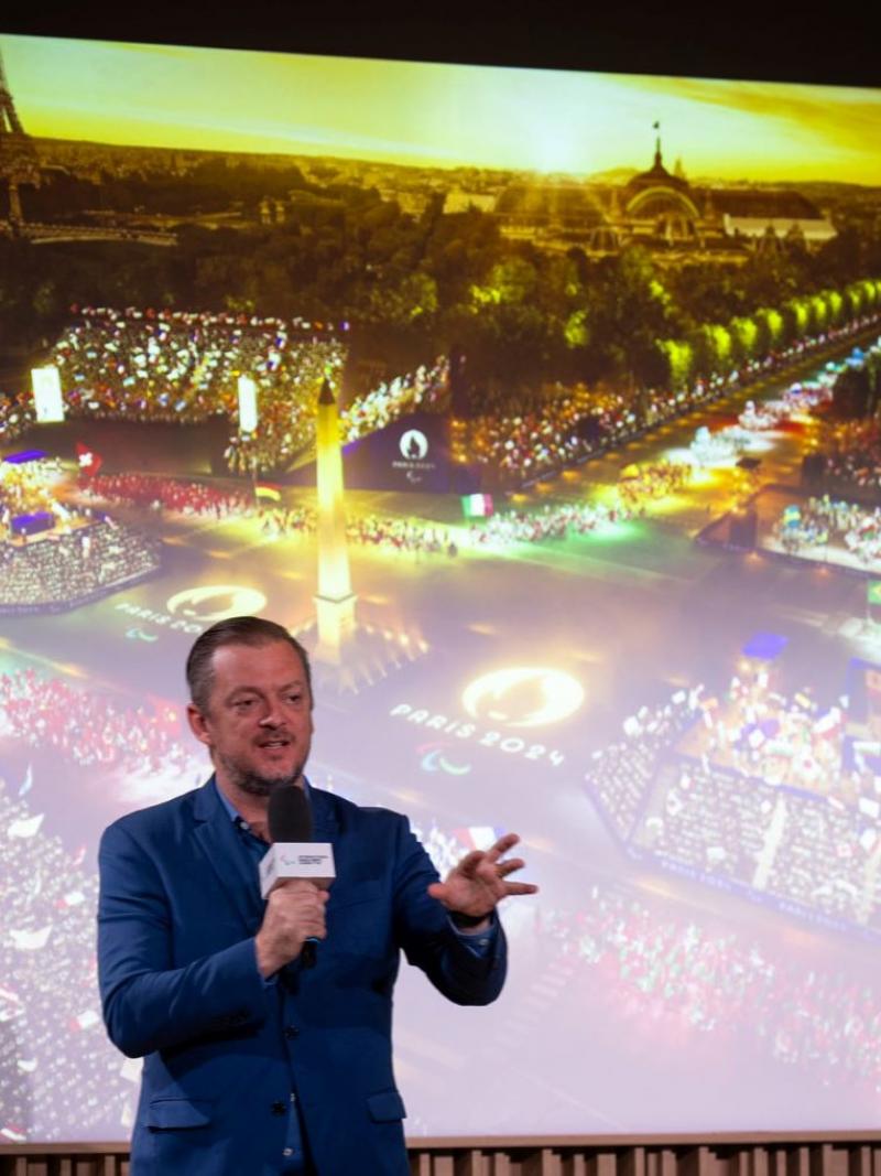 IPC President Andrew Parsons speak in front of a screen showing the Opening Ceremony of the Paris 2024 Paralympic Games