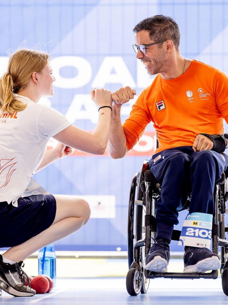 A male athlete and a female official wearing a Tshirt that says "Team NL boccia" celebrate