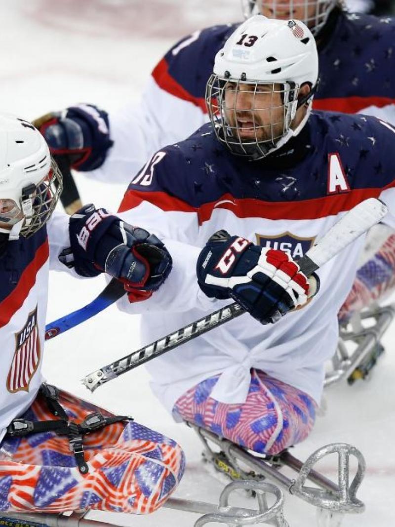 An ice sledge hockey player skates up to his teammate to celebrate.