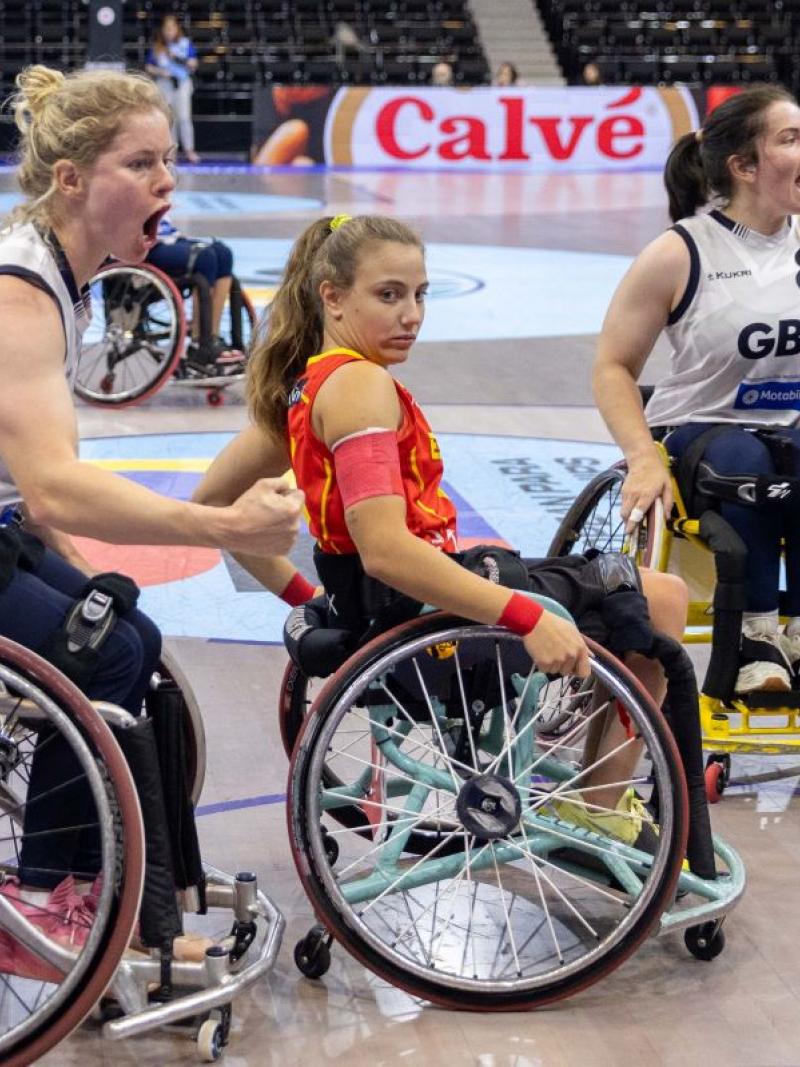 Three female wheelchair basketball players on court.