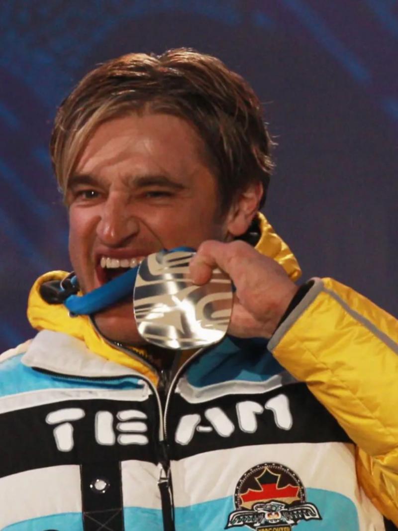 A picture of a man beating his silver medal during a medal ceremony