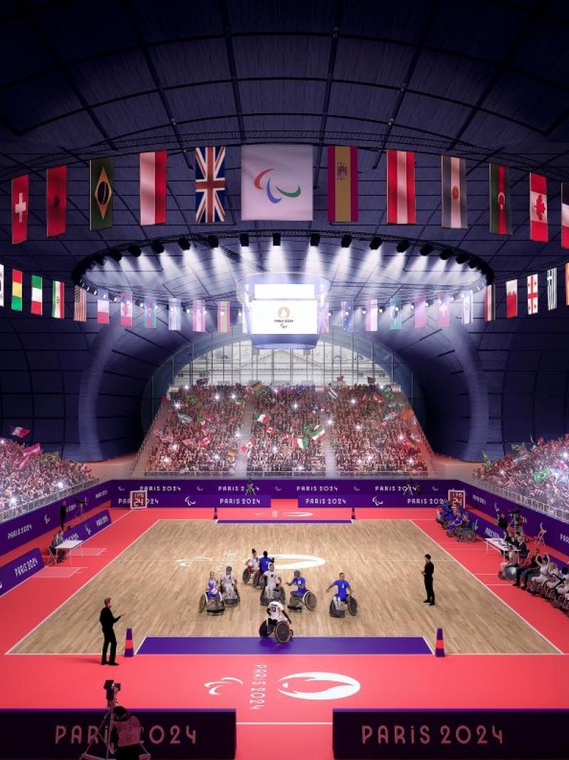 a wide shot of a wheelchair rugby arena with spectators in the stands 