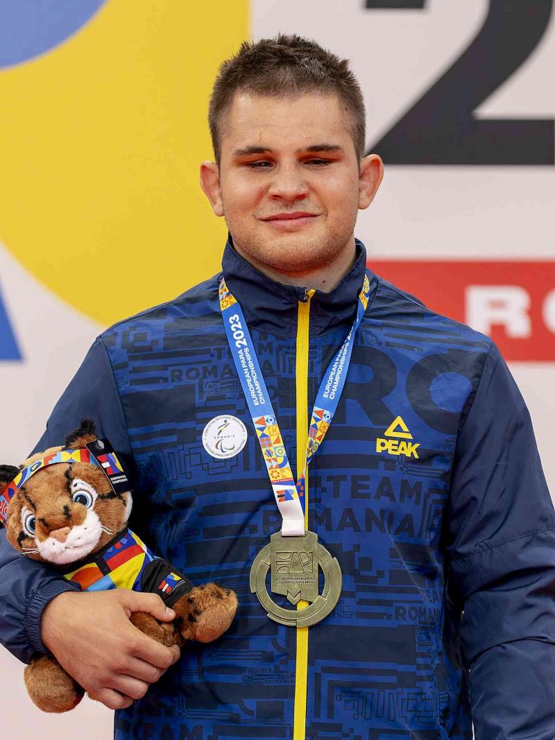 Florin Alexandru Bologa with his gold medal and mascot on the podium