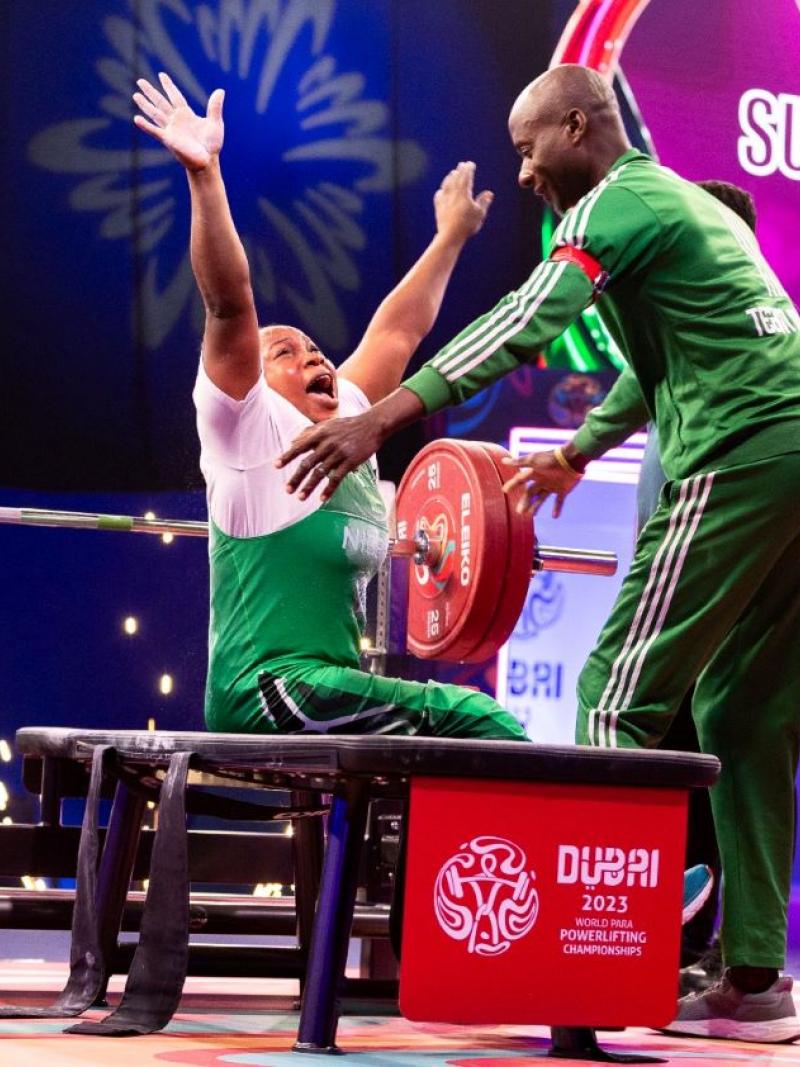 A female powerlifter celebrating with her male coach