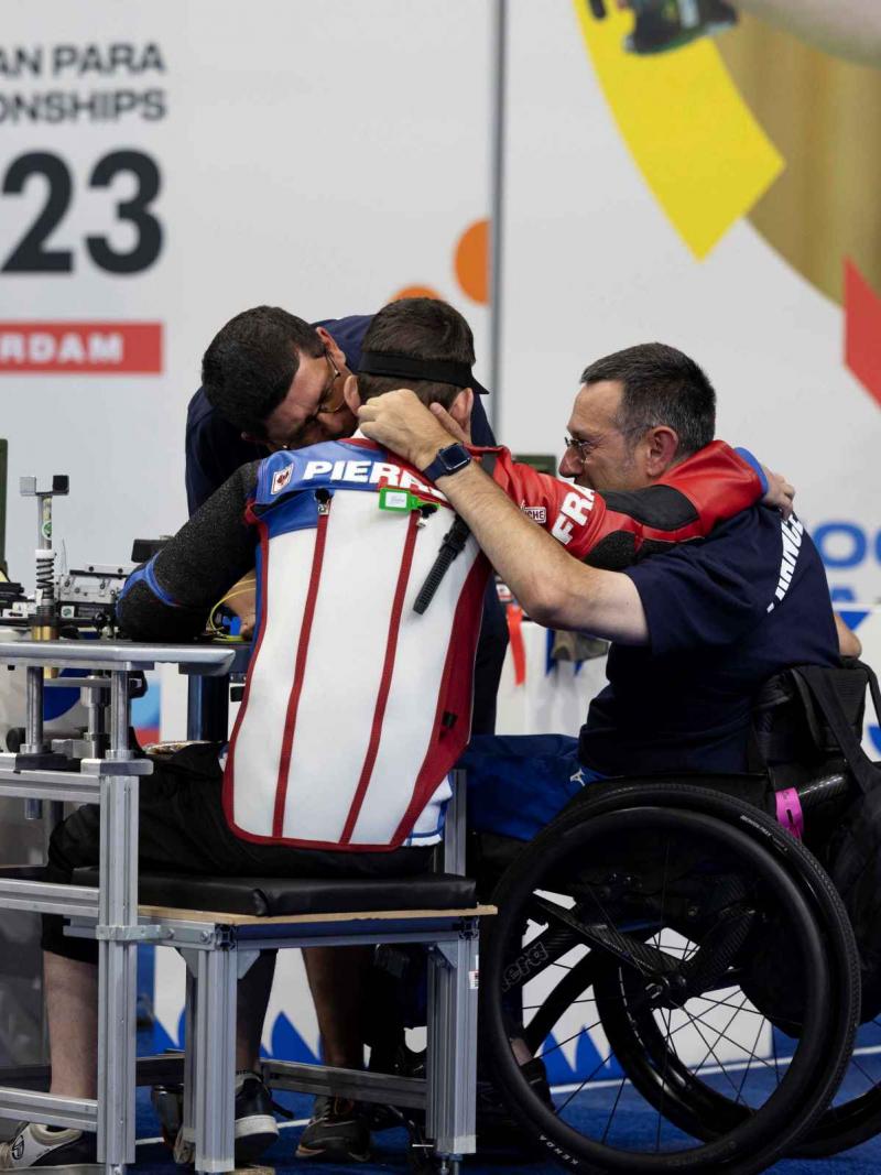 A man in a wheelchair chair hugging two other men