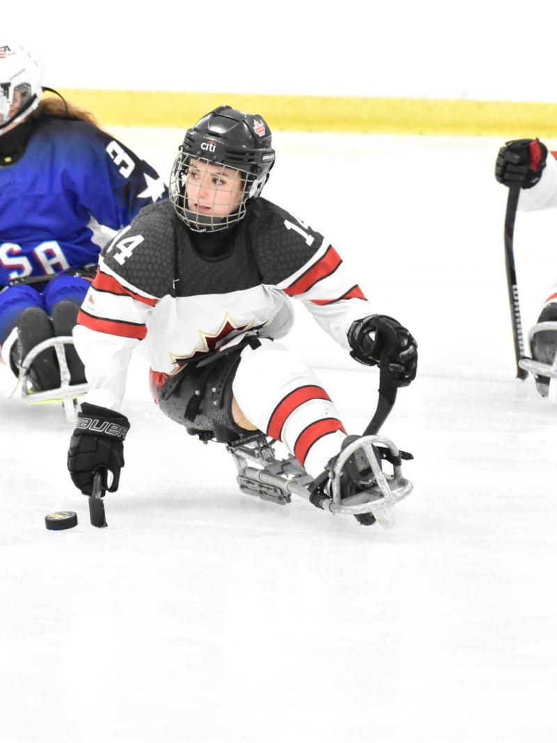 A Canadian female Para ice hockey player on ice followed by a USA player