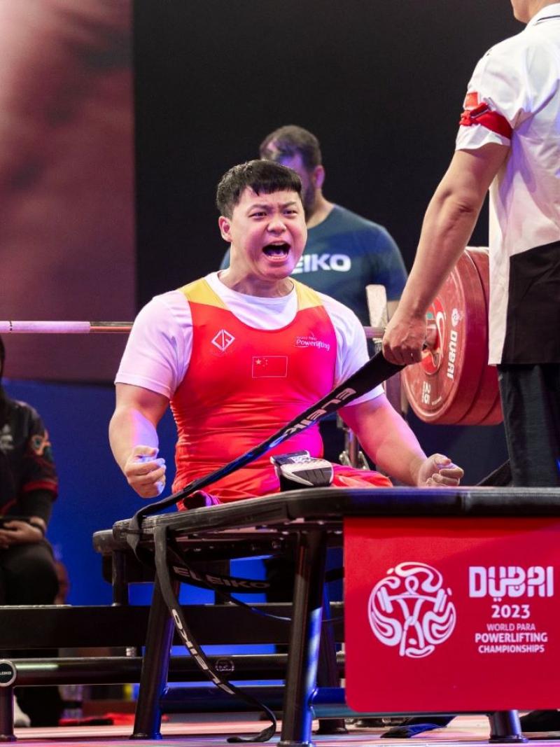 A male athlete celebrating on a bench press during a Para powerlifting event