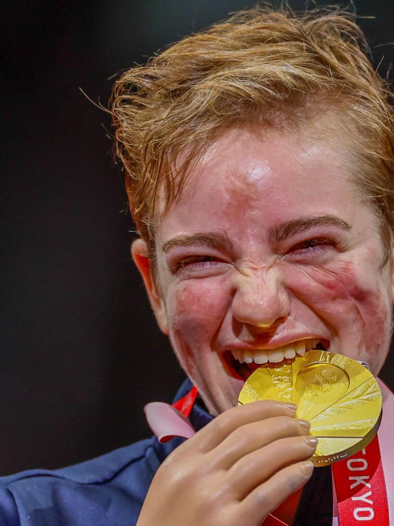 A female athlete bites a gold medal