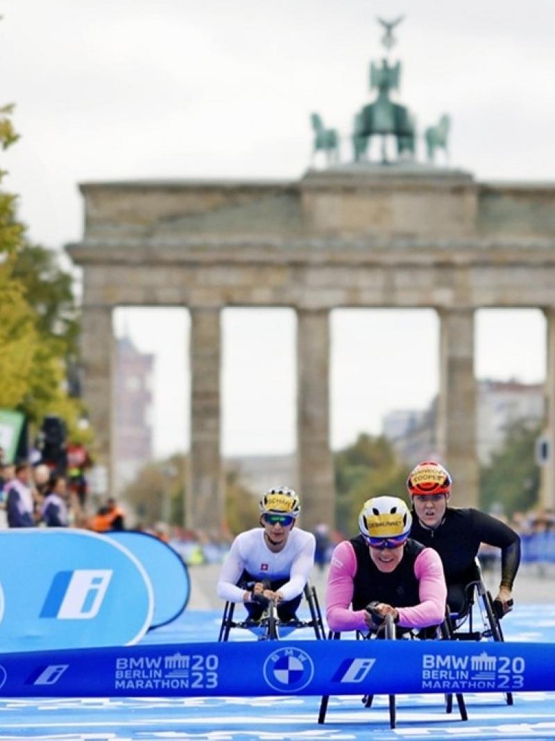 A female wheelchair racer crossing the finishing line of the Berlin Marathon ahead of two competitors