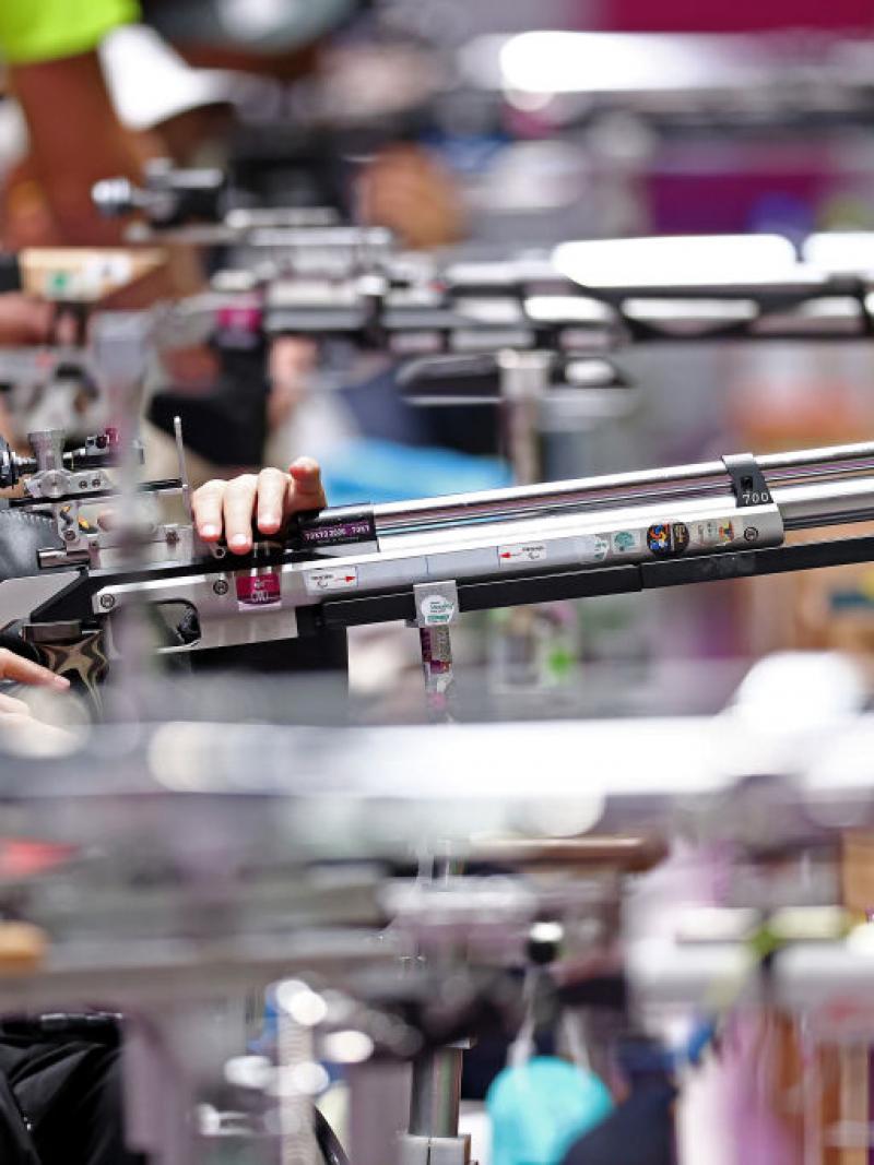A male rifle shooter in the middle of other athletes in a shooting range