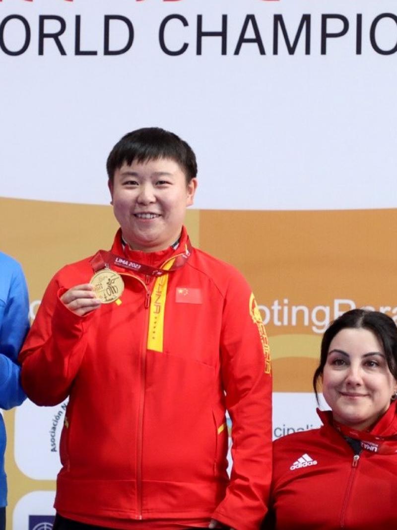 Two women standing next to a seated woman showing their medals