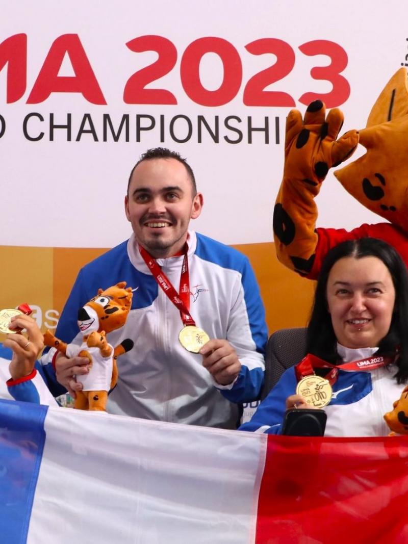 Two men and a woman holding the French flag near a mascot