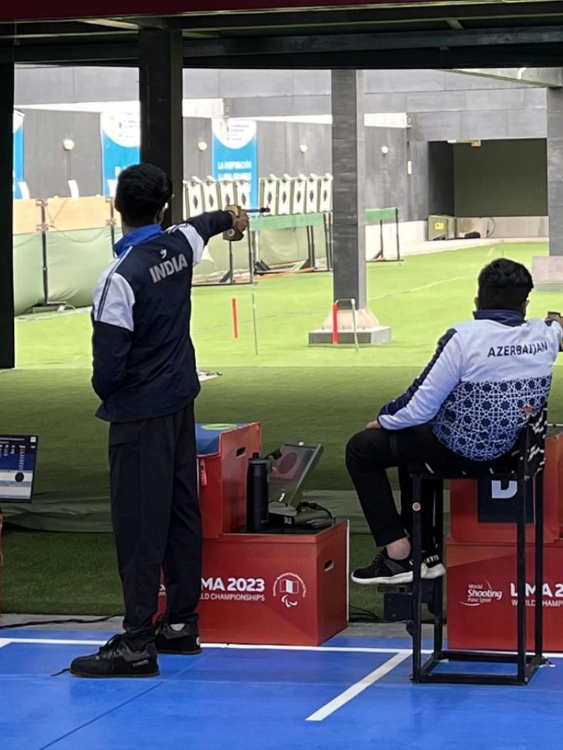 A standing man and a man in a wheelchair competing in a shooting range
