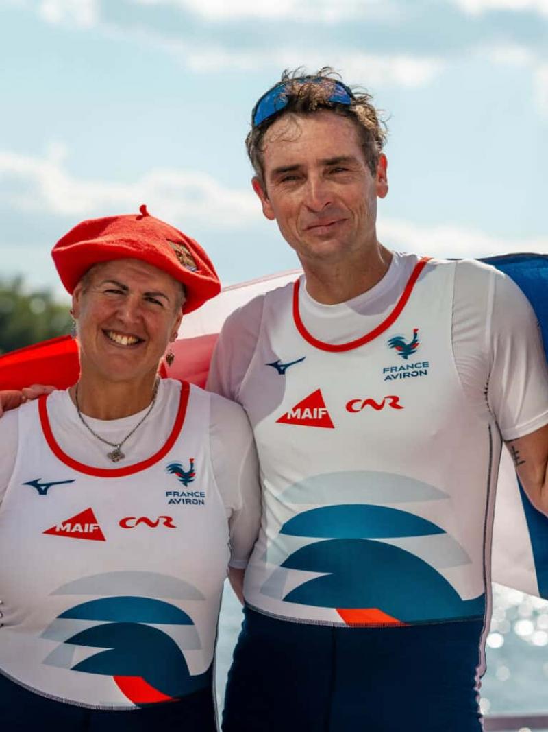 A male and a female Para rower pose for a photograph while holding the French flag.