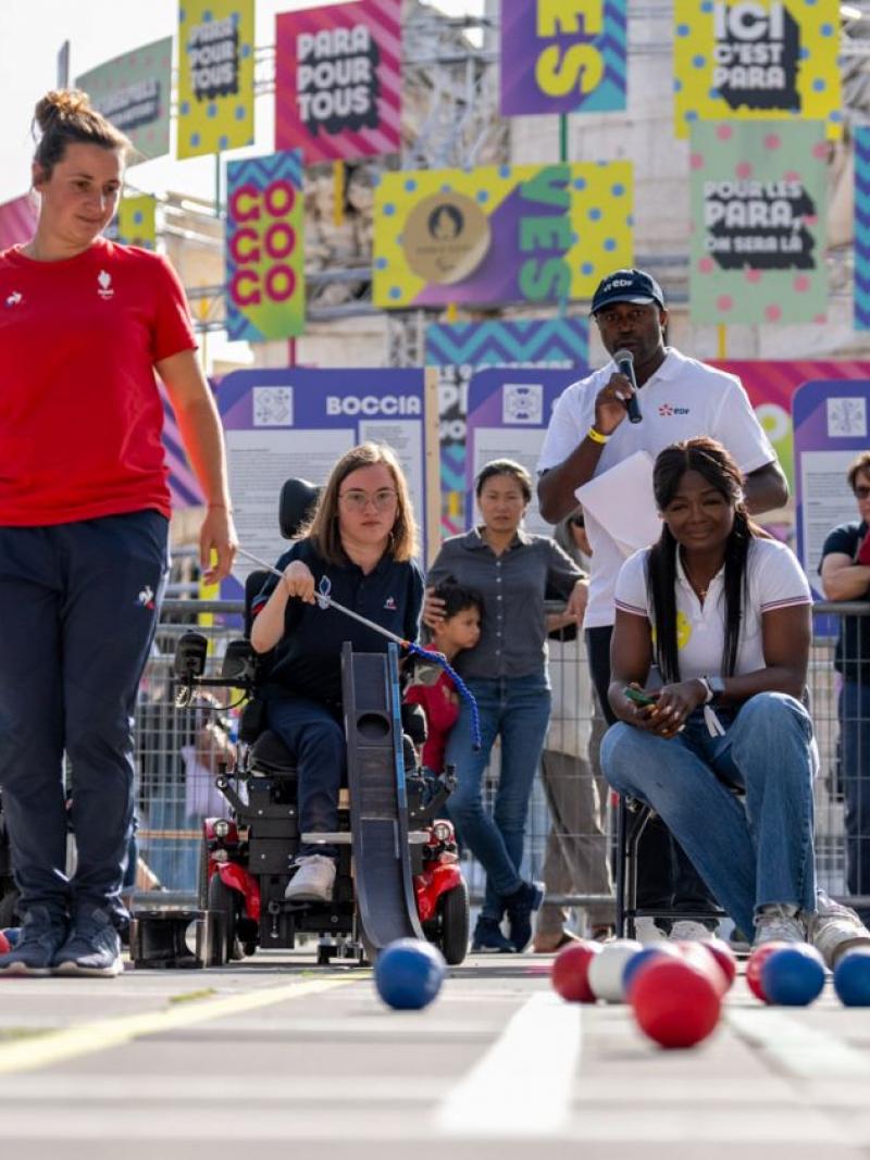 People demonstrate playing boccia in front of a crowd