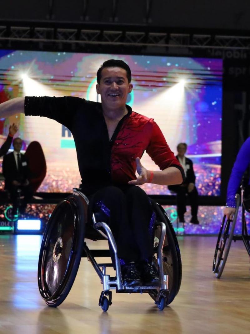A male wheelchair dancer in a competition with another male dance in the background