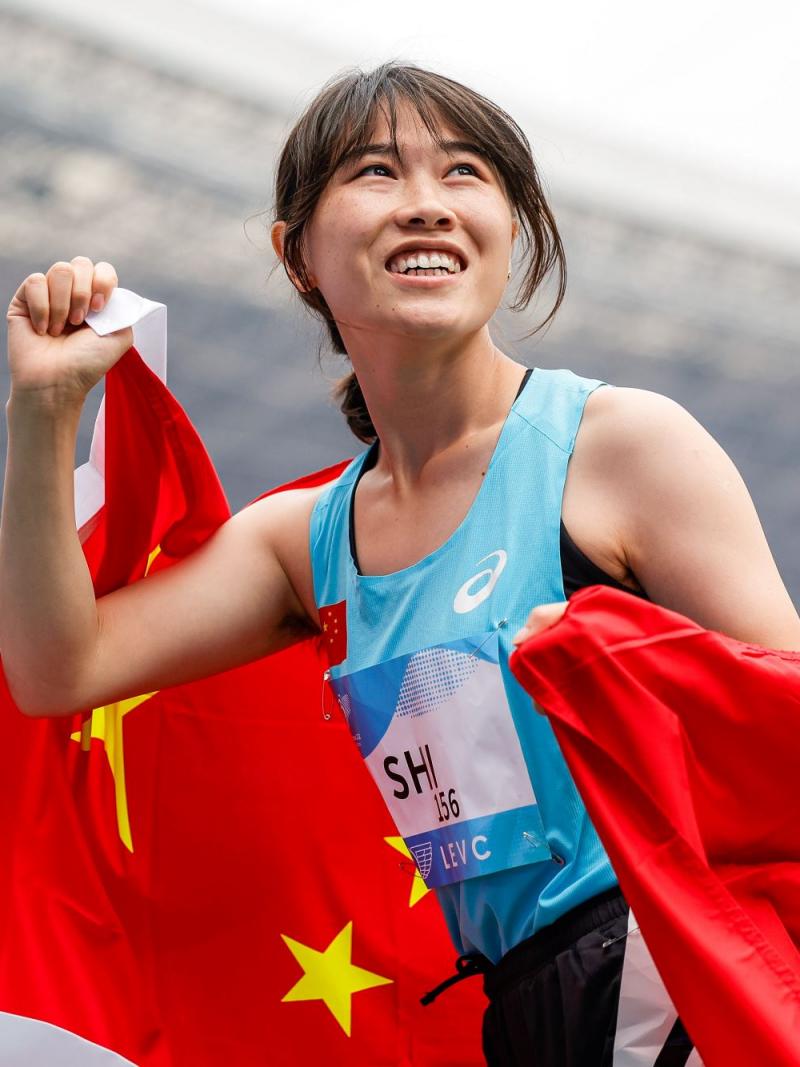 A female athlete with a Chinese flag in a athletics stadium