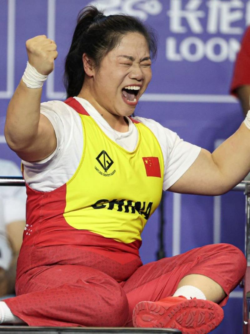 A female powerlifter celebrating on a bench press