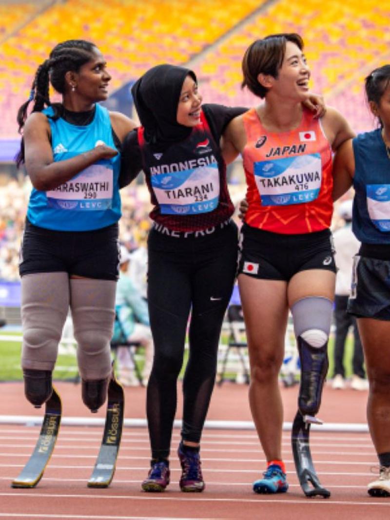 Four female athletes with running blades look to their left side