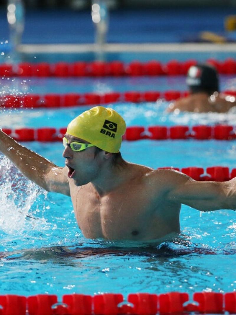 A male swimmer with a cap of Brazil celebrating in the pool