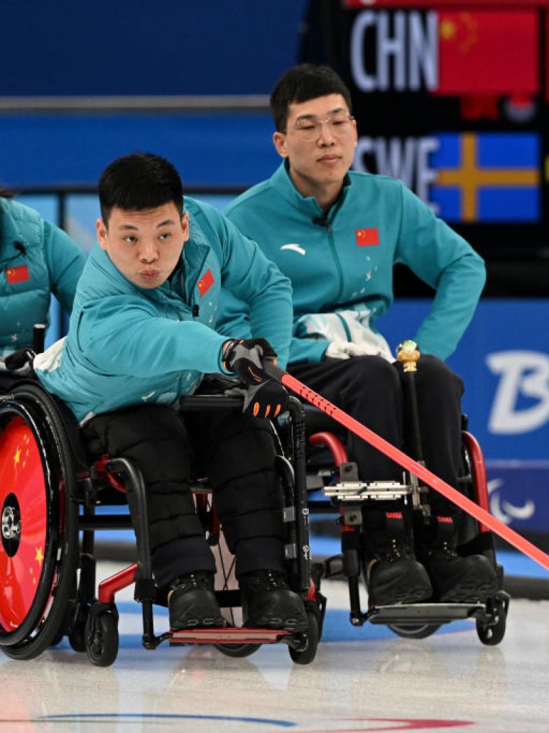Three wheelchair curling athletes on the ice at Beijing 2022