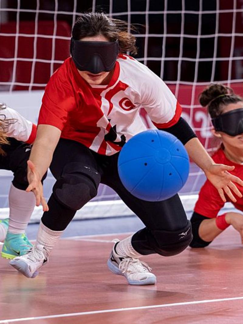 Three female players wearing eyeshades compete in goalball