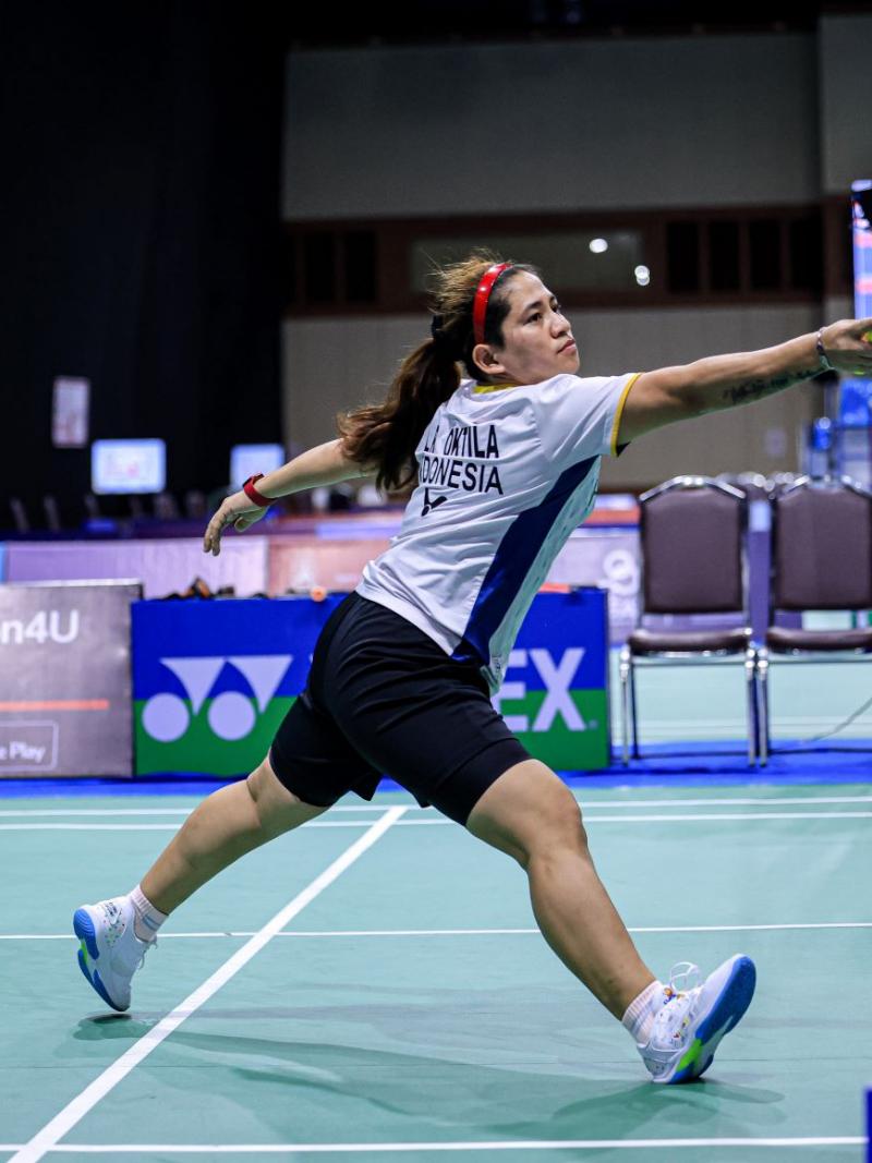 A female Para badminton player reaches for the shuttle during a Para badminton match
