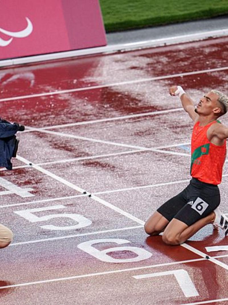 A male athlete celebrates in front of a camera operator on the track after winning a race.