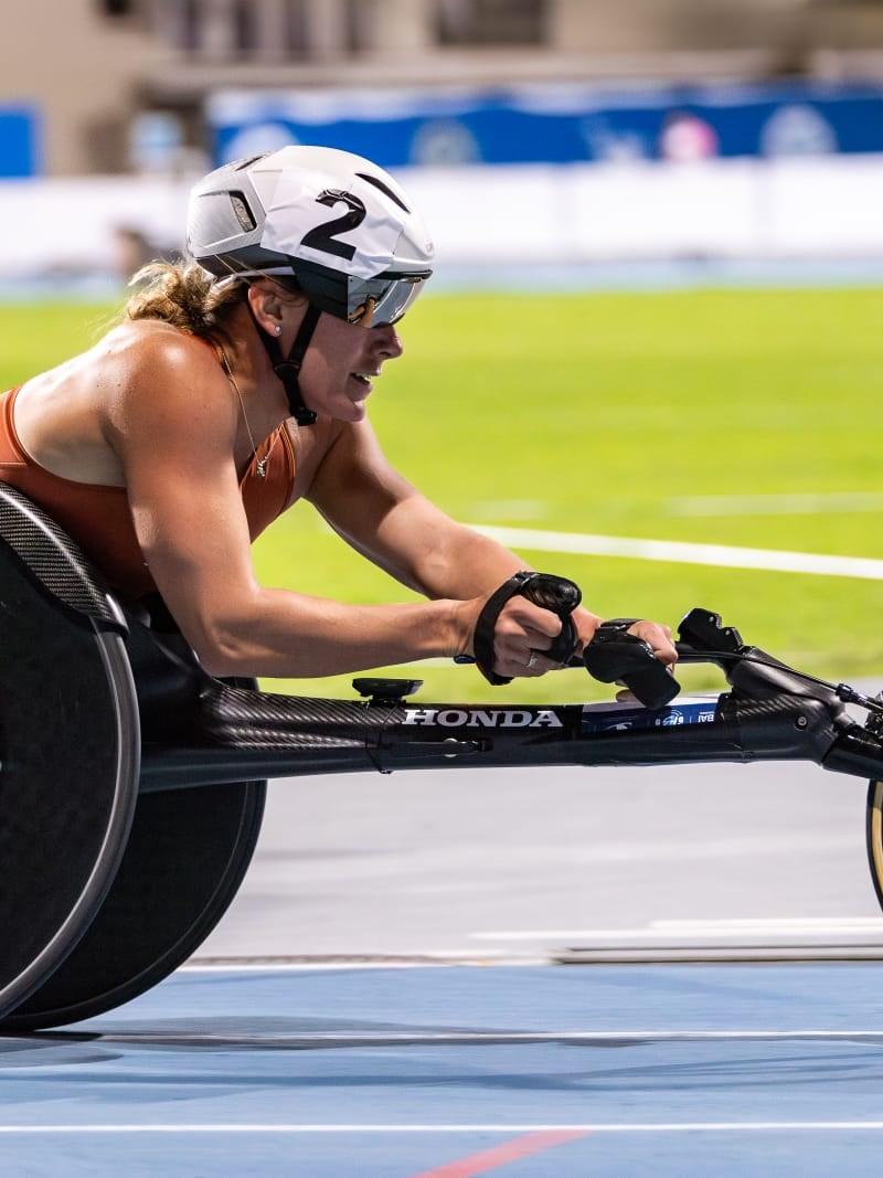 A female wheelchair racer on a blue athletics track