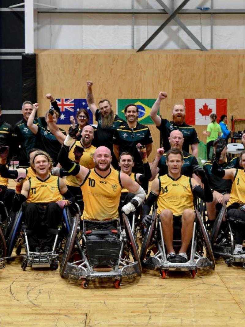 About 20 wheelchair rugby players and officials pose for a photograph