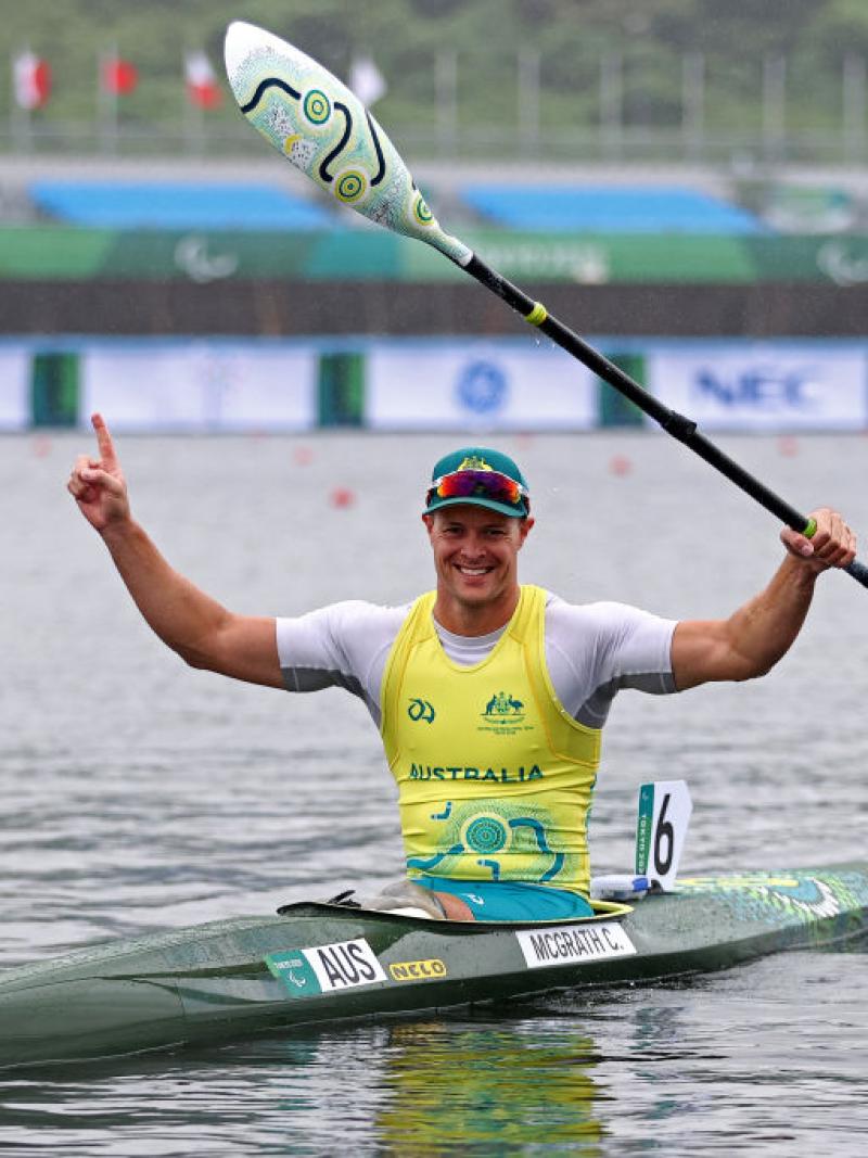 Male Para canoeist Curtis McGrath raises his arms in celebration