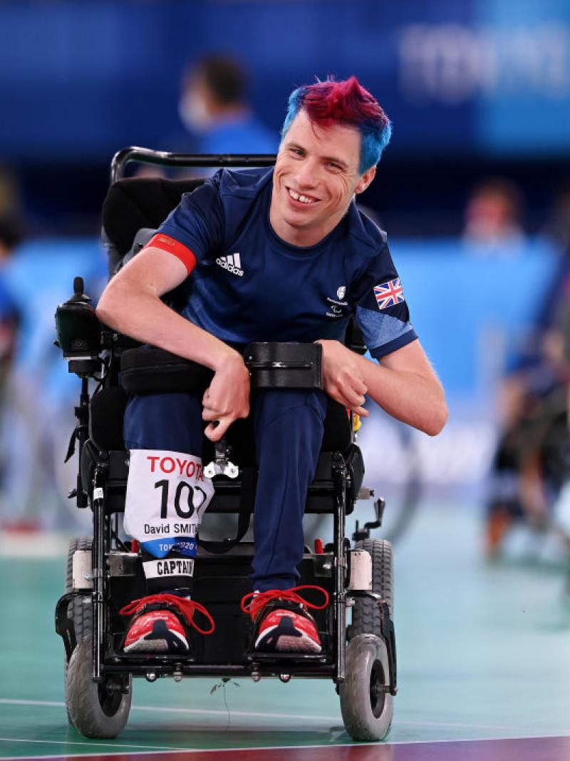 Boccia player David Smith smiles at the camera from a powered wheelchair 