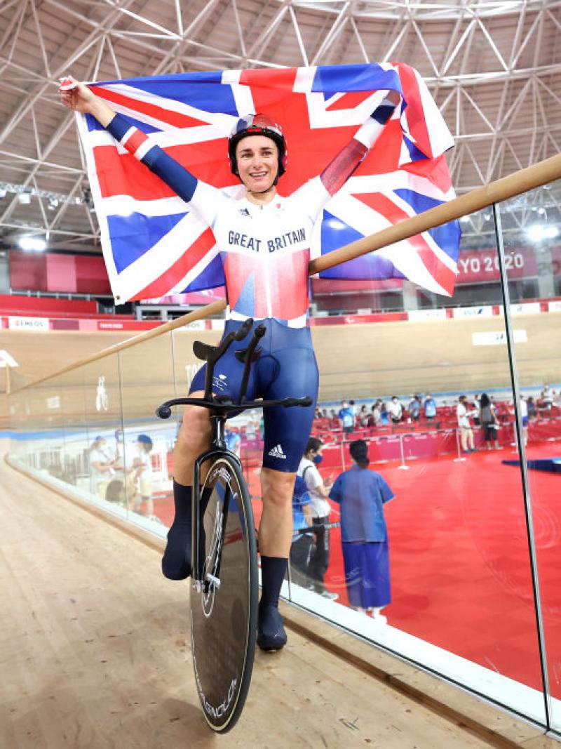 A female Para cyclist celebrates by holding the British flag
