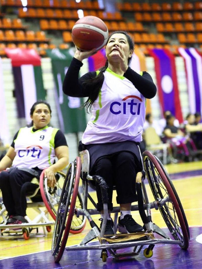 A female wheelchair basketball player is about to throw the ball during a match.