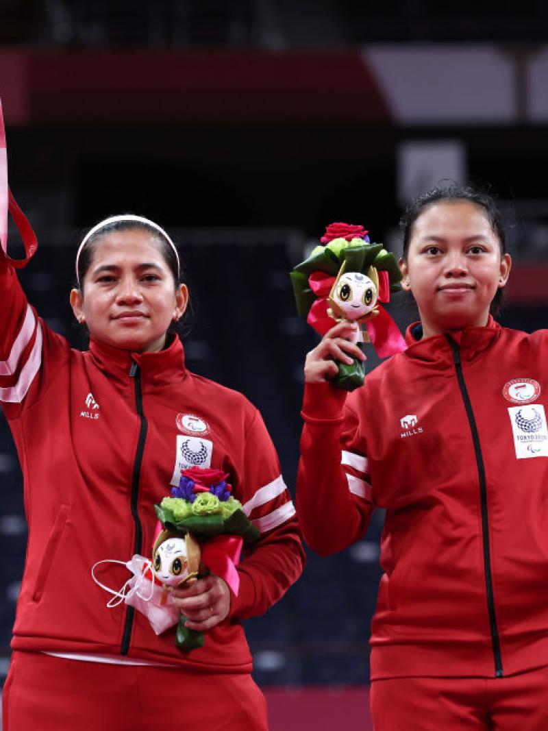 Leani Ratri Oktila and badminton partners raise their medals on the podium