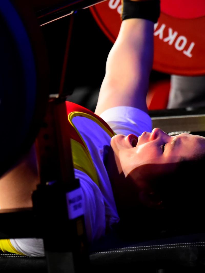 A female powerlifter raising the bar in a competition