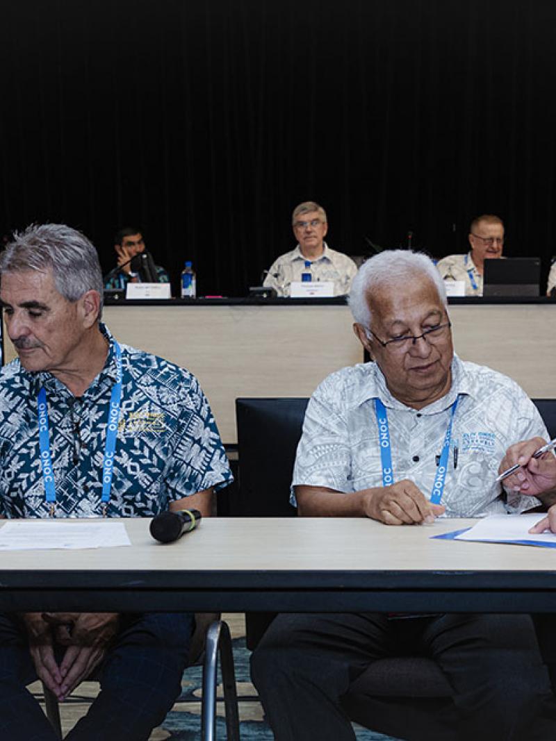 Four male officials sign a document