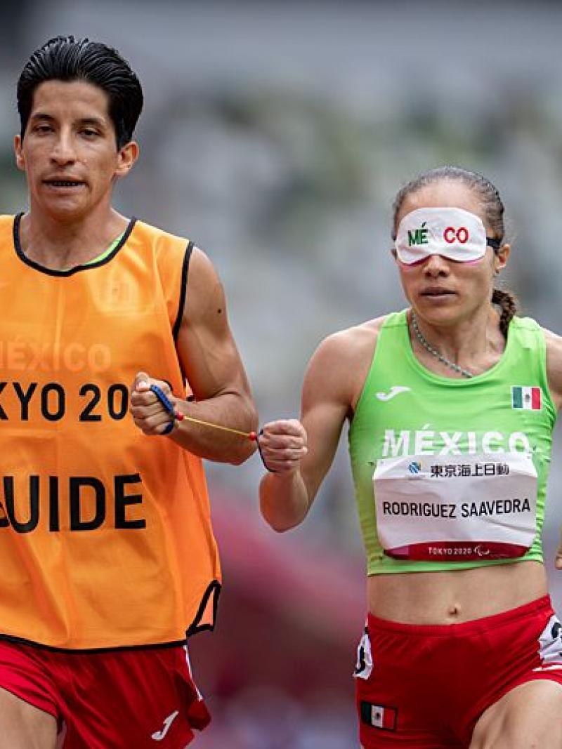 A Para athlete runs with his guide