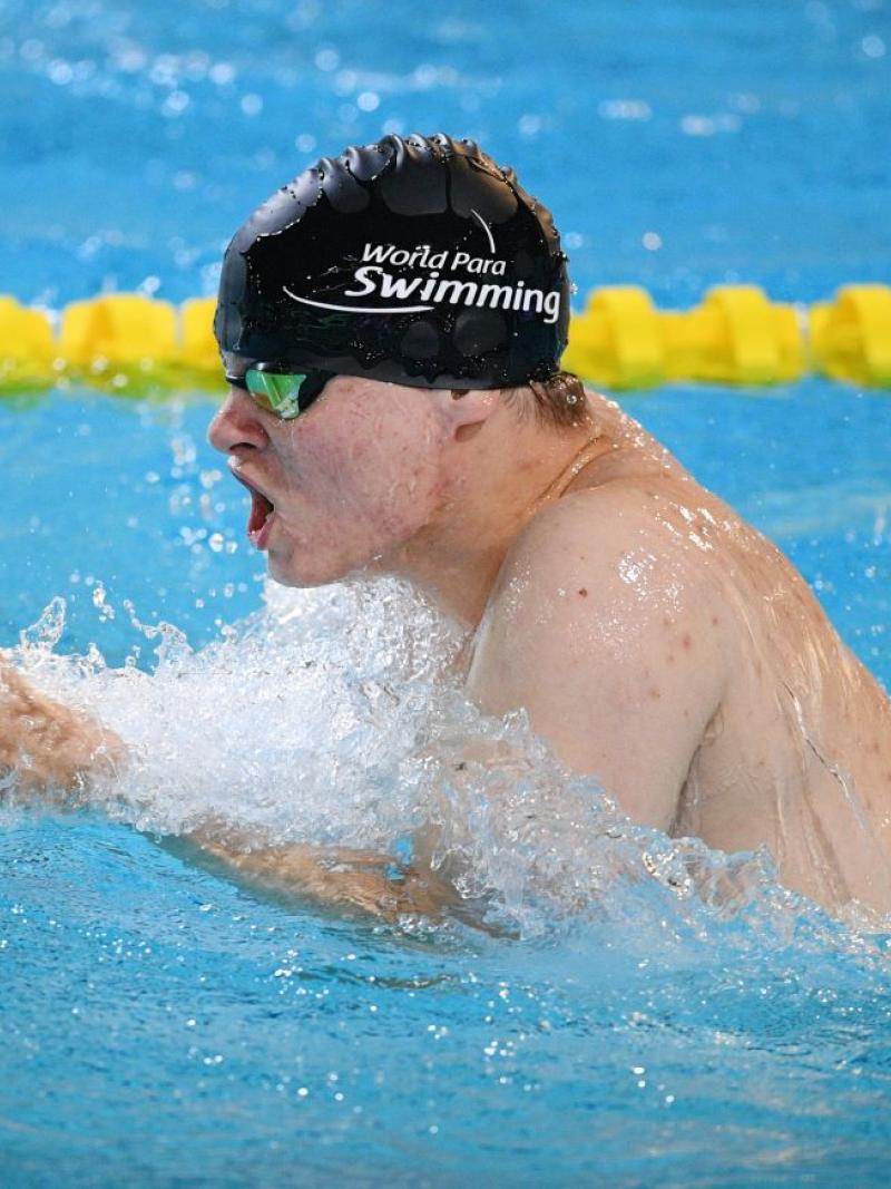 A man with black cap swimming breaststroke 