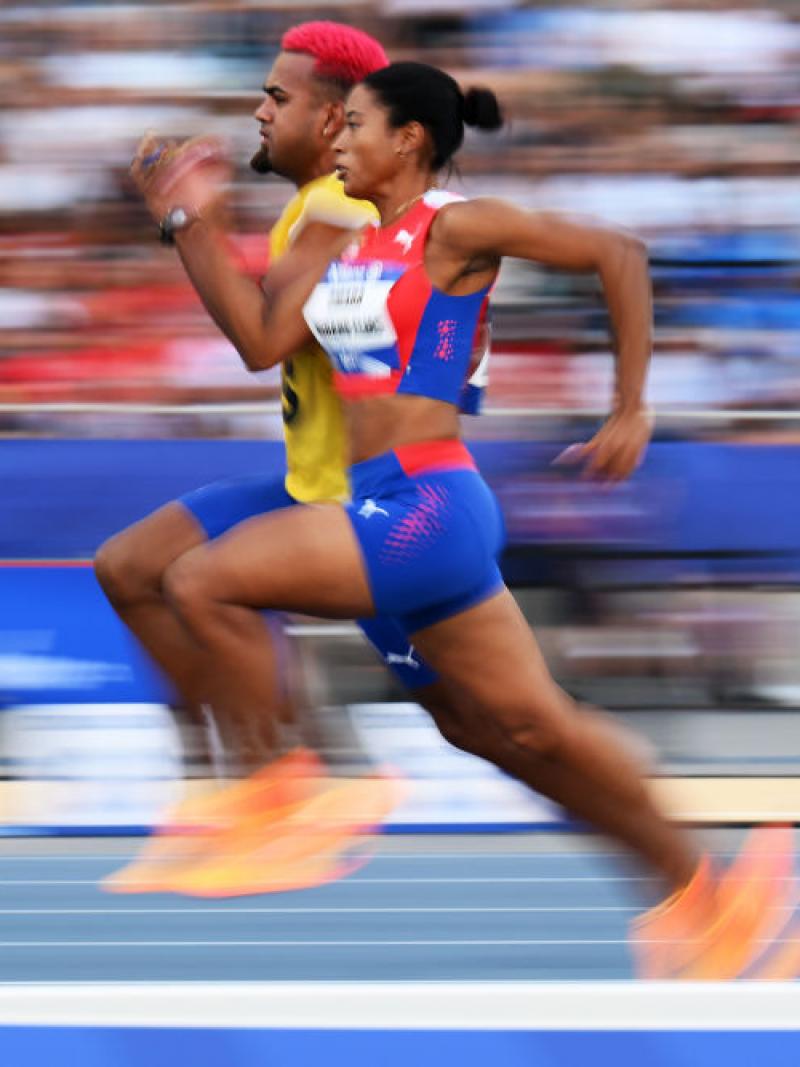 A female athlete running on a track next to her male guide