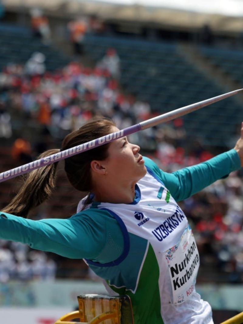 A female athlete throwing a javelin in a stadium