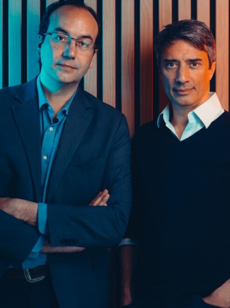 Two men posing in front of a colourful wall