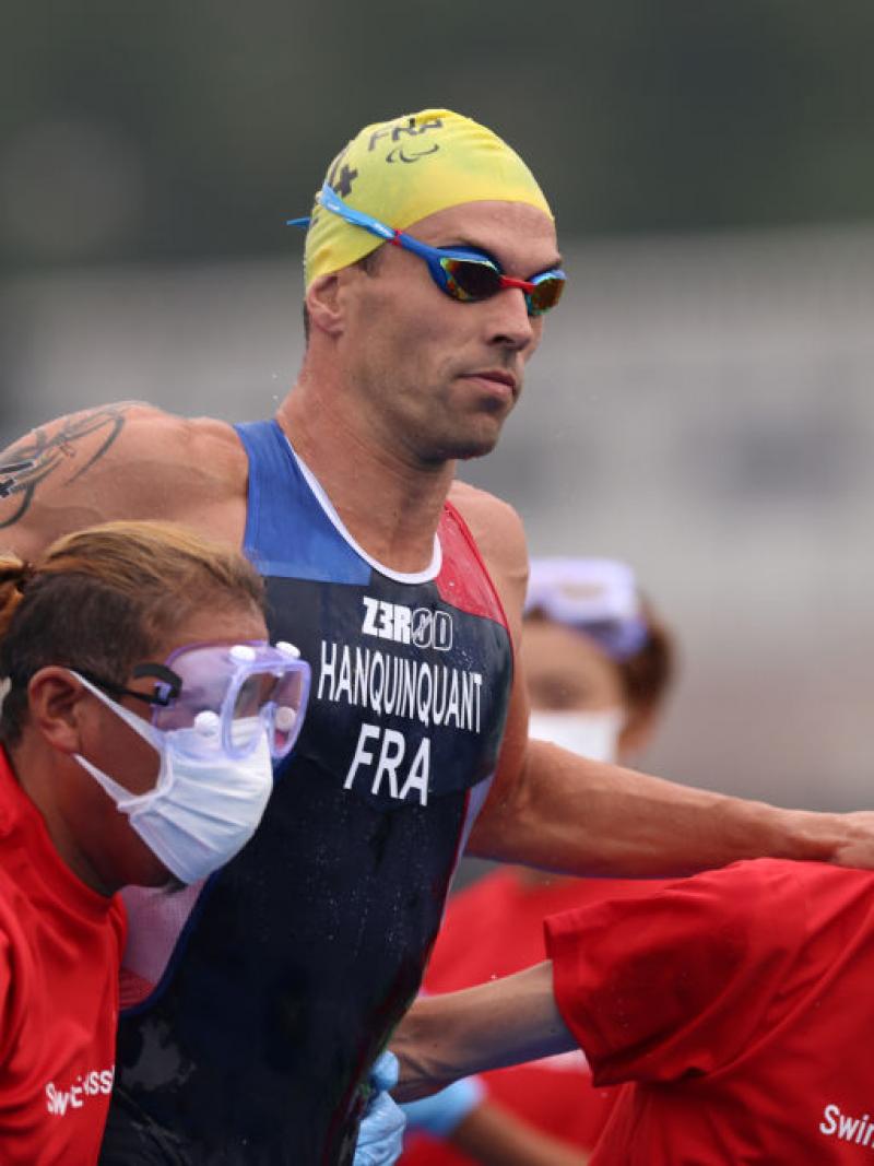 A male triathlete is assisted by staff after the swim segment at the Tokyo 2020 Paralympics