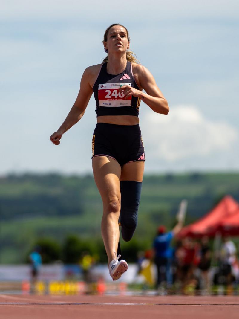 A female athlete with a prosthetic leg crossing the finish line