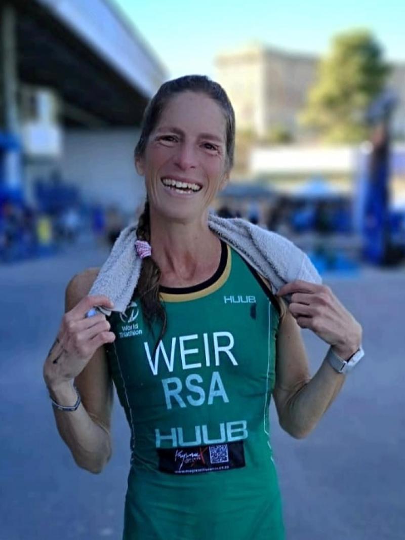 A female triathlete wearing South Afirca's green uniform smiles 